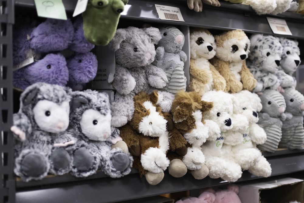 Rows of soft Warmies plush animals, some wearing tiny Fairway Cares shirts